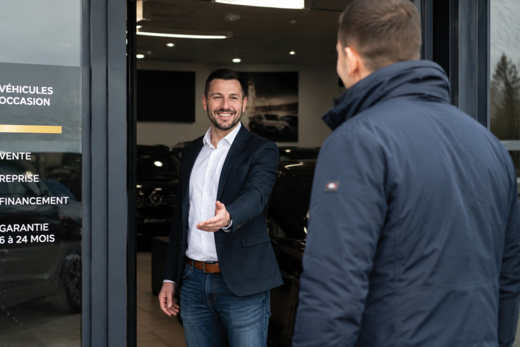 Vendeur de véhicules d'occasion accueillant un client devant le showroom SV Automobile à Orléans avant un achat de voiture d'occasion.